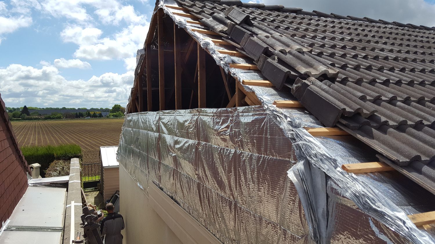 Pose de l'isolant sur le pignon, rives de toiture dégagées — chantier Schatz Rénovation à Nemours